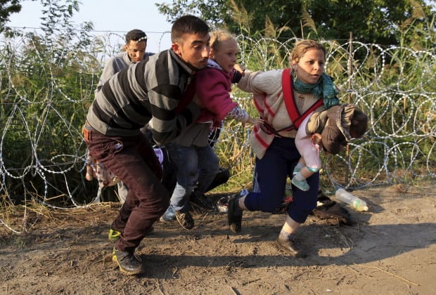Syrian migrants run after crossing under a fence as they enter Hungary, at the border with Serbia, near Roszke